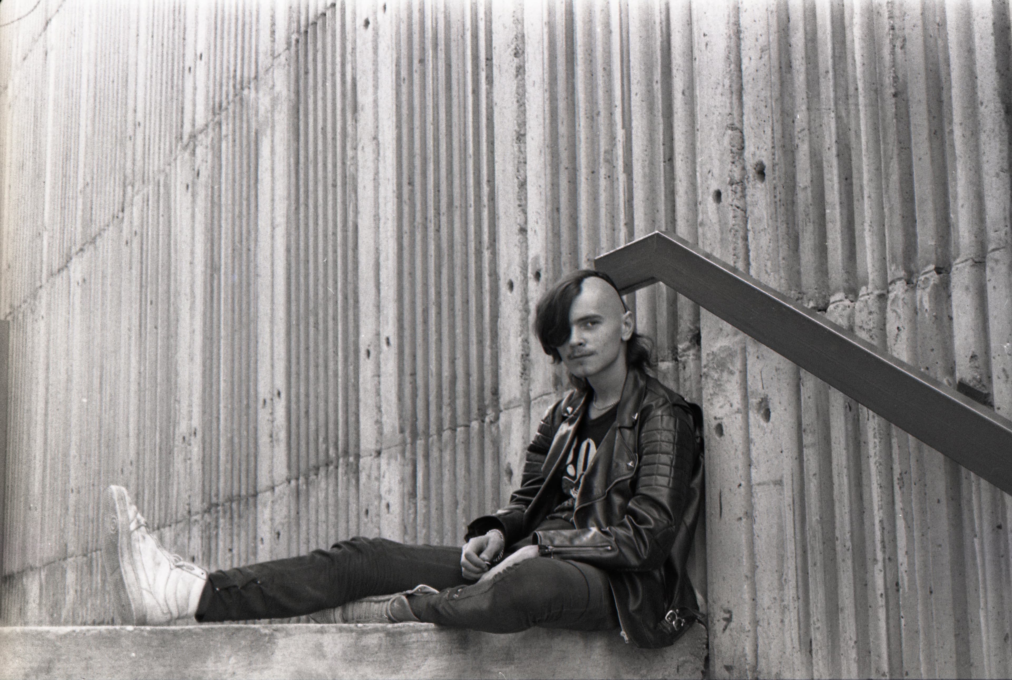 View of a black-and-white photograph of a punk rocker sitting on steps in Bratislava in 1990